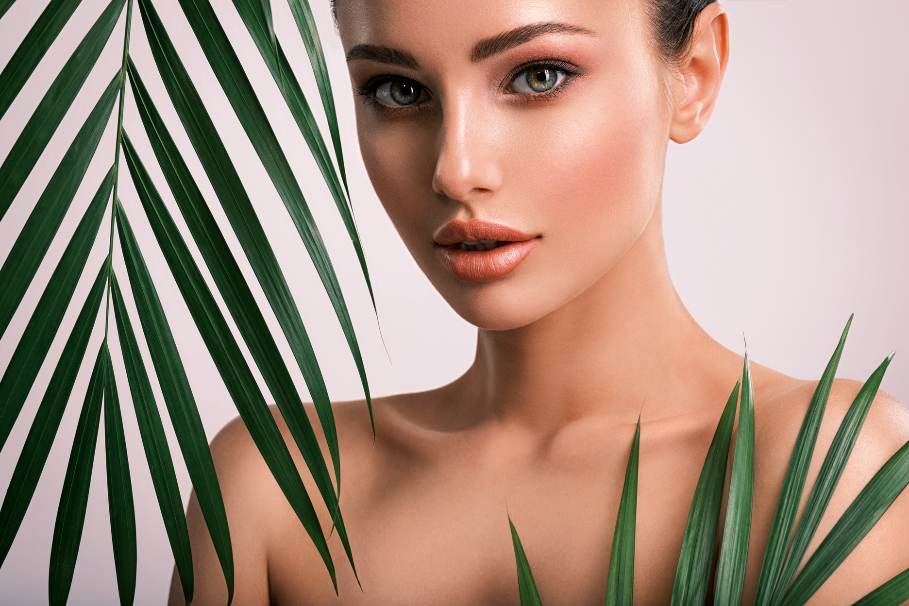 Young Beautiful Woman with Green Leaves near Face and Body. Skin