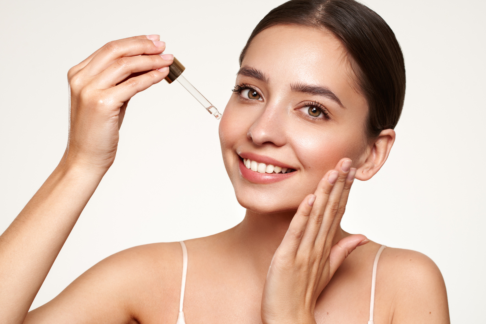 Young beautiful woman applying face serum